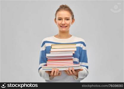 education, travel and tourism concept - happy smiling teenage student girl with books over grey background. happy smiling teenage student girl with books