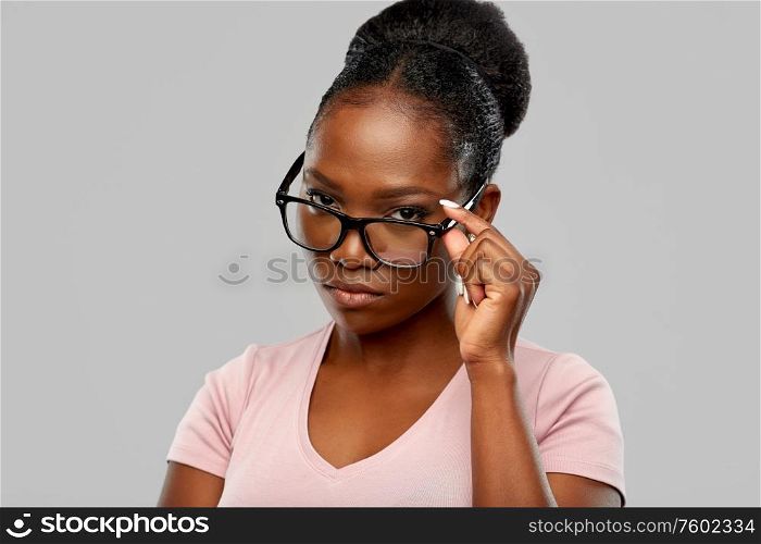 education, vision and people concept - african american woman in glasses over grey background. african american woman in glasses