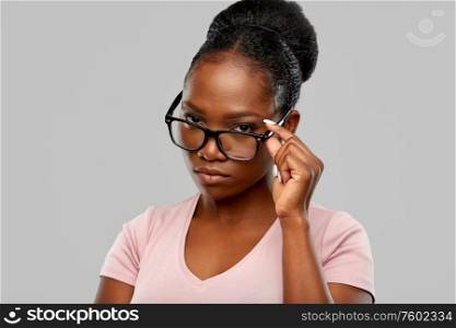 education, vision and people concept - african american woman in glasses over grey background. african american woman in glasses