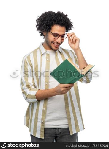 education, vision and people concept - happy smiling young man in glasses reading book over white background. happy young man in glasses reading book