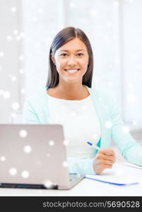 education, winter, technology and people concept - smiling young woman with laptop computer and notebook indoors
