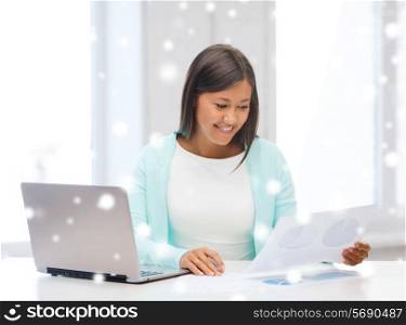 education, winter, technology and people concept - smiling young woman with laptop computer and papers indoors