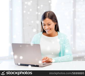 education, winter, technology and people concept - smiling young woman with laptop computer indoors