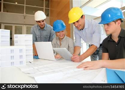 Educator with students in architecture working on electronic tablet