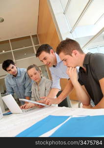 Educator with students in architecture working on electronic tablet