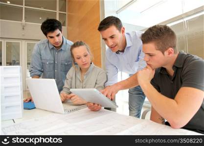 Educator with students in architecture working on electronic tablet