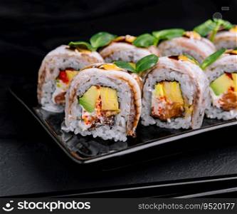 Eel sushi rolls on black plate