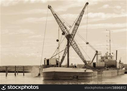 Effect vintage. Dredger ship navy working to clean a navigation channel