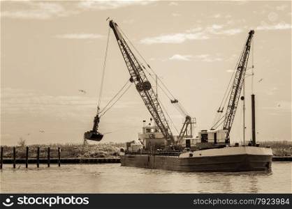 Effect vintage. Small dredge marine, which is cleaning a navigation channel