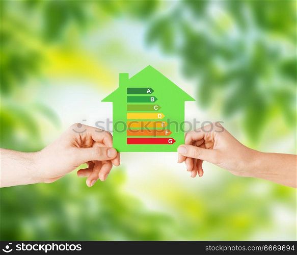 efficiency and home concept - closeup of female hands holding green paper house with energy saving rating over natural background. hands holding green paper house. hands holding green paper house