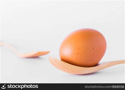 Egg and wooden spoon isolated on white background.