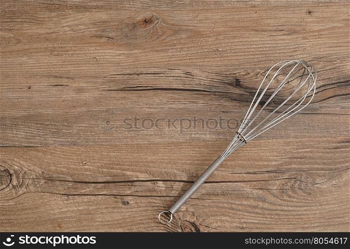 Egg beater, whisk, isolated on a wooden background
