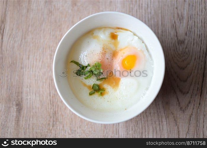 egg breakfast , soft-boiled eggs on white bowl with pepper, coriander on wooden table, Onsen tamago egg - egg microwave