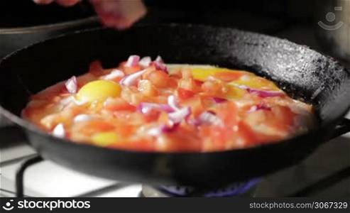 Egg frying in a pan. Adding onion slices.