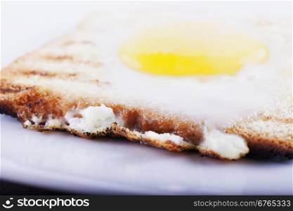 Egg in a hole over white plate, focus over first border, horizontal image
