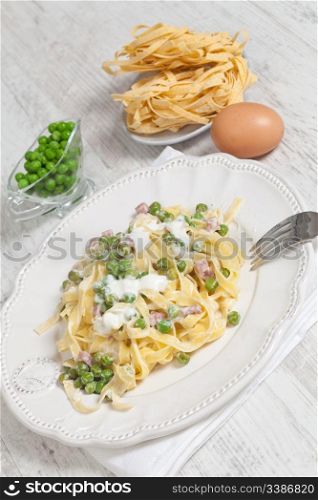 Egg noodles with cream, ham and green peas