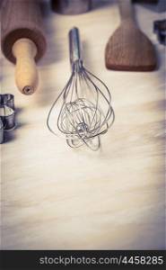 Egg whisk and bake tools on wooden background, close up, toned