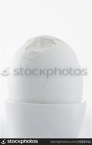 Egg with broken shell in egg cup, close up, studio shot