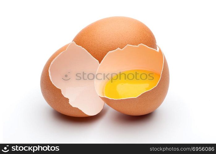 Egg yolk in egg shell. Cracked and whole raw brown eggs on white background