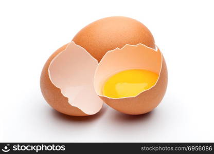 Egg yolk in egg shell. Cracked and whole raw brown eggs on white background