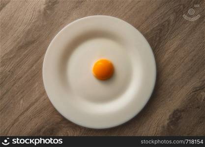 egg yolk on white plate and wooden table. egg yolk on white plate