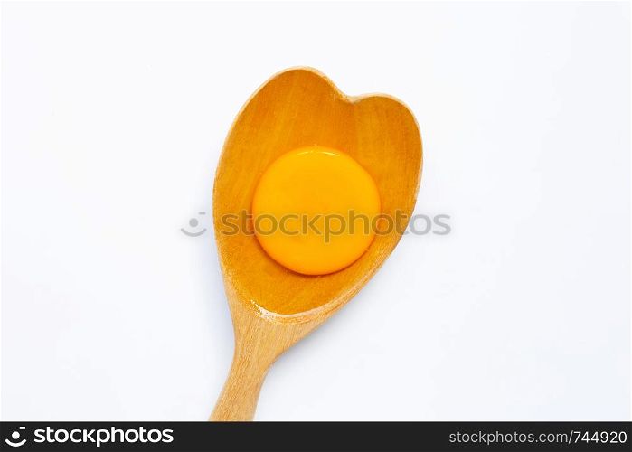 Egg yolk on wooden spoon on white background.
