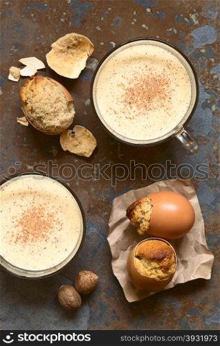 Eggnog cupcakes baked in eggshell and eggnog drink in glass cups, photographed overhead with natural light (Selective Focus, Focus on the top of the cupcakes and the drinks)