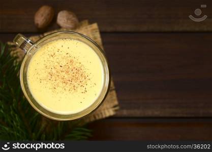 Eggnog with freshly grated nutmeg on the top, photographed overhead on dark wood with natural light (Selective Focus, Focus on the top of the eggnog)