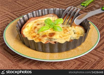 Eggs and bacon tart with basil leaves