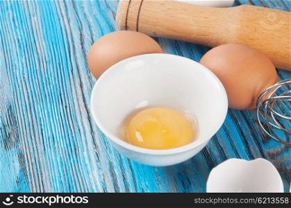 Eggs and egg yolk in a white dish on a blue wooden background