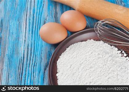 Eggs and flour on a blue wooden background