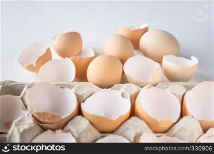 Eggs and shkarlupka eggs in a box on a white background.. Eggs and shkarlupa halves of eggs in a tray.