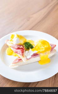 Eggs Benedict breakfast- toasted English muffins, ham, poached eggs, with buttery hollandaise sauce