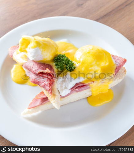 Eggs Benedict breakfast- toasted English muffins, ham, poached eggs, with buttery hollandaise sauce