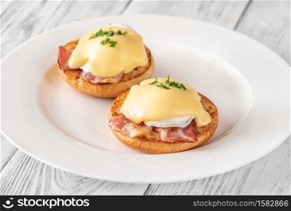 Eggs Benedict with bacon on white plate