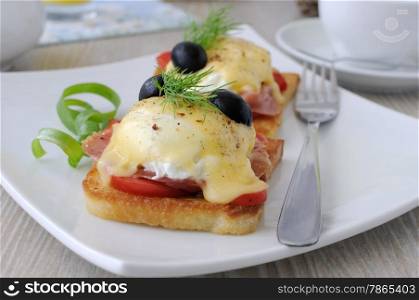 Eggs Benedict with ham and tomato on toast with cheese and olives