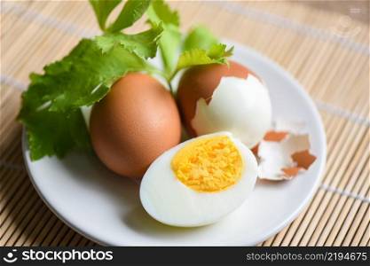 Eggs breakfast, fresh peeled eggs menu food boiled eggs and eggshell on white plate decorated with leaves green celery on wooden background, egg cooking healthy eating concept