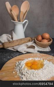 Eggs, dough, flour and rolling-pin on wooden table background. Preparation for making homemade ravioli pasta.