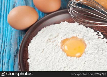 Eggs, egg yolk and flour on a blue wooden background
