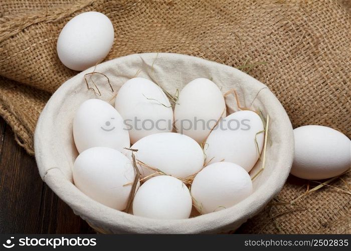 Eggs in a bowl with grass on burlap cloth still life