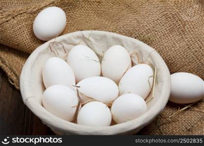 Eggs in a bowl with grass on burlap cloth still life