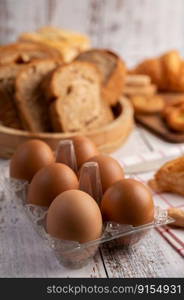 Eggs in a Plastic panels and bread that is placed on a white wooden plate.