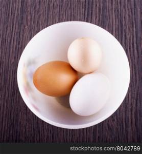 Eggs in cup over wooden table, square image