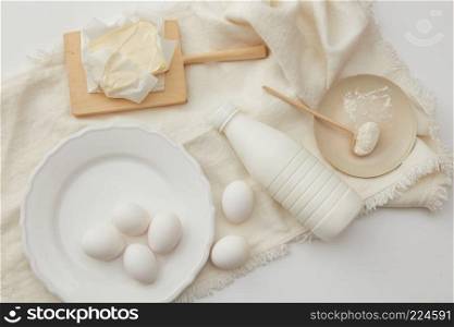 Eggs, milk, flour and butter to bake a cake on a white napkin , flat lay. baking cake ingredients
