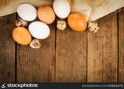 Eggs on textile tablecloth over rustic wooden table with copyspace