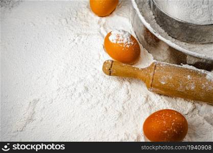 Eggs, rolling pin and sieve on the table with flour. On a white background.. Eggs, rolling pin and sieve on the table with flour.