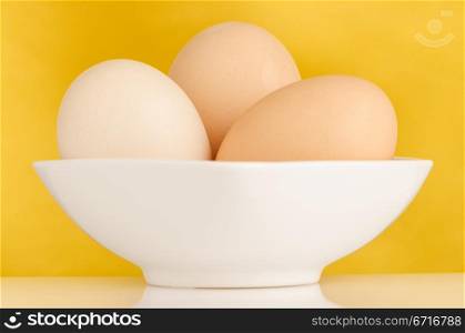 Eggs,Three eggs in the bowl on a yellow background.