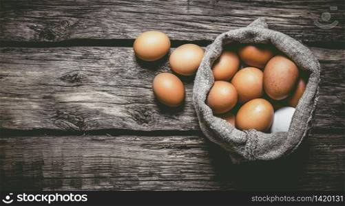 Eggs with an old bag. On a wooden table. Free space for text . Top view. Eggs with an old bag. On wooden table.