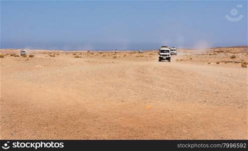 Egypt, Black Desert. Moving off-road vehicle with a panoramic view on the stone desert . Tracks on the sand from the automotive rubber.