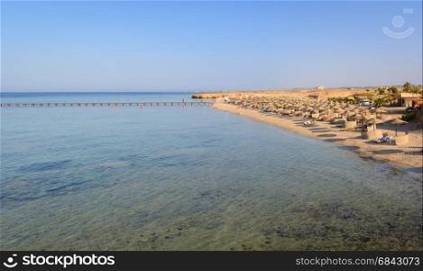 Egyptian beaches with typical parasols in the background and red sea in frontground